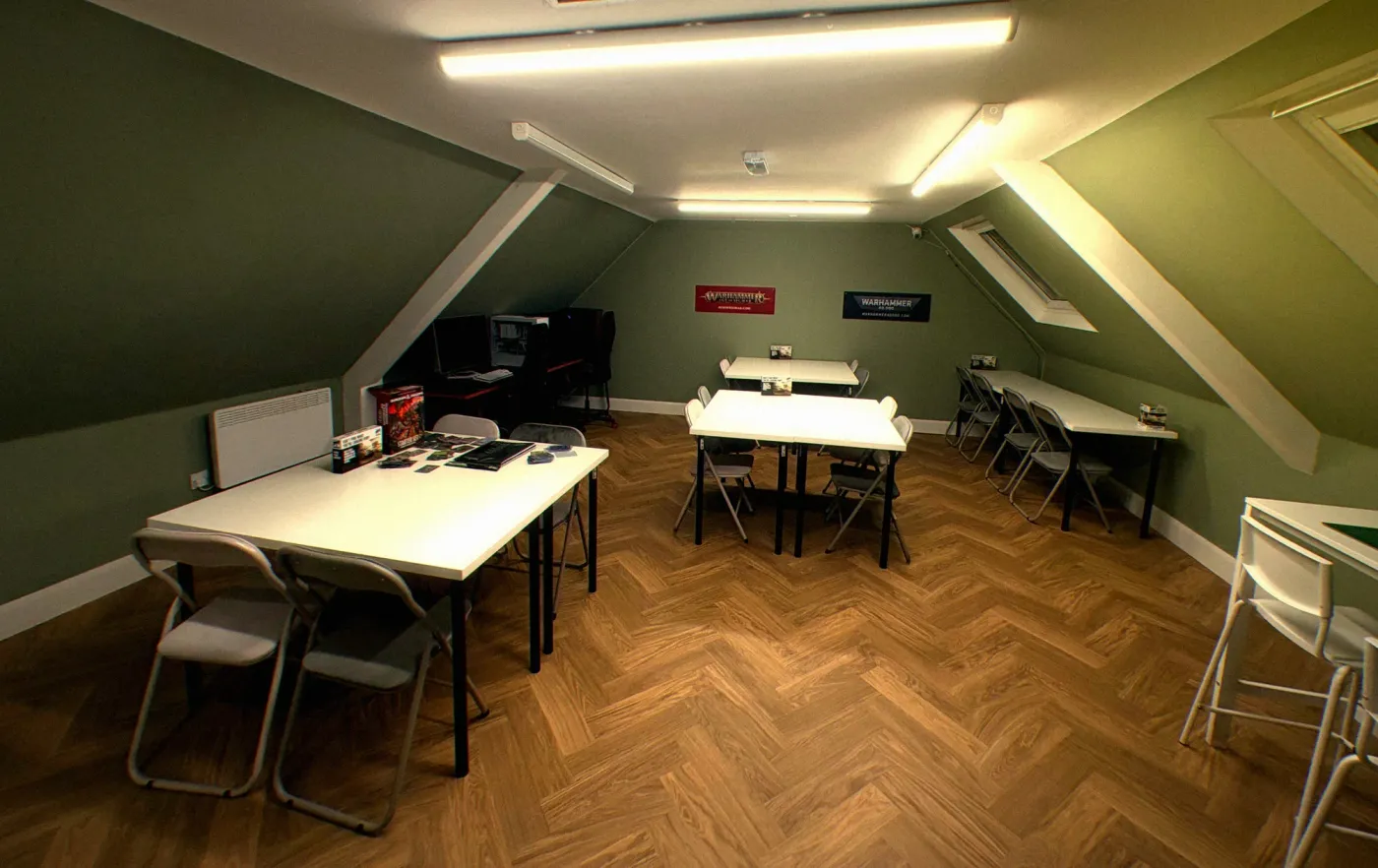 The upstairs gaming room at GG Entertainment, with card tables, gaming PCs and Warhammer banners